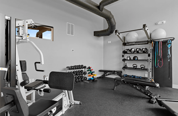 A gym with a variety of equipment including a weight bench, dumbbells, and a cable machine.